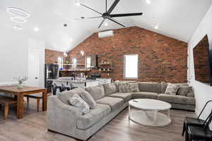 Living room featuring ceiling fan, sink, brick wall, and light wood-type flooring