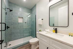 Bathroom with toilet, vanity, a shower with door, and hardwood / wood-style floors