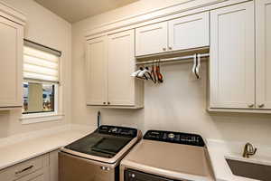 Laundry room featuring cabinets, independent washer and dryer, and sink