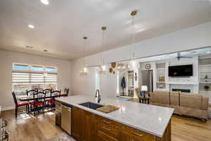 Kitchen with decorative light fixtures, sink, stainless steel dishwasher, and an island with sink