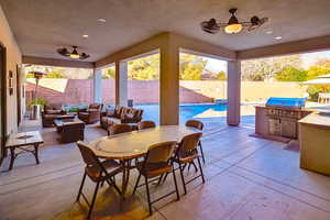 View of patio featuring an outdoor kitchen, an outdoor hangout area, a fenced in pool, ceiling fan, and area for grilling