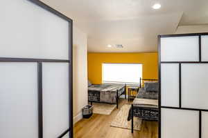 upstairs apartment over detached garage: Sleeping area with room dividers  featuring a textured ceiling and light hardwood / wood-style flooring