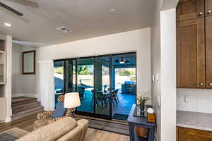 Family room featuring a textured ceiling, ceiling fan, a healthy amount of sunlight, and hardwood / wood-style floors with slinding glass doors that open completely to covered patio.