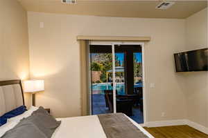 Owner's Bedroom with access to exterior covered patio & pool area with hardwood / wood-style floors