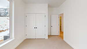 Unfurnished bedroom with baseboards, a closet, and light colored carpet