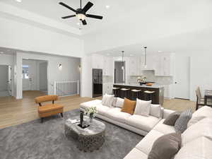 Living area with recessed lighting, a towering ceiling, light wood finished floors, and ceiling fan