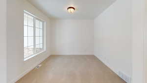 Empty room with light carpet, baseboards, and visible vents