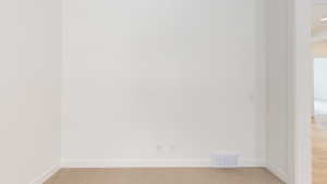 Unfurnished room featuring baseboards, visible vents, and light colored carpet