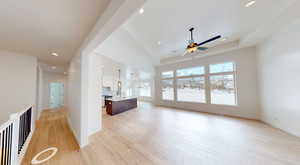 Living room with light wood-type flooring, a raised ceiling, a healthy amount of sunlight, and recessed lighting