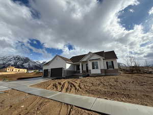 View of front facade with concrete driveway, a mountain view, a garage, and brick siding
