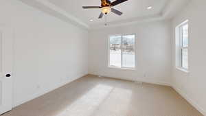 Empty room featuring recessed lighting, a raised ceiling, and baseboards
