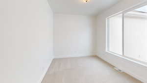 Unfurnished room with light carpet, baseboards, visible vents, and a wealth of natural light