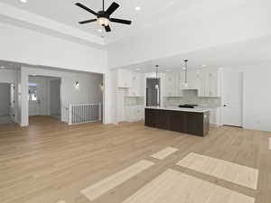 Kitchen with light countertops, a sink, backsplash, open floor plan, and light wood-style flooring