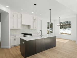 Kitchen with light countertops, white cabinetry, range with electric cooktop, custom range hood, and decorative backsplash