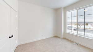 Unfurnished bedroom with baseboards, visible vents, and light colored carpet