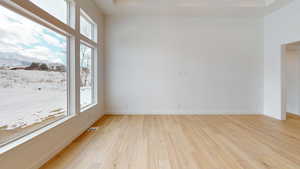 Empty room with light wood-type flooring, visible vents, and baseboards