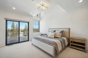 Bedroom with vaulted ceiling, light colored carpet, and access to outside