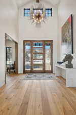 Foyer entrance featuring beamed ceiling, an inviting chandelier, light wood-type flooring, high vaulted ceiling, and french doors