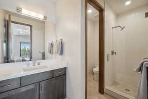 Bathroom with toilet, vanity, and a shower with shower door