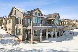 Snow covered property featuring stone siding, a standing seam roof, and metal roof