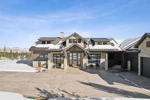 View of front facade with stone siding, a chimney, and a mountain view