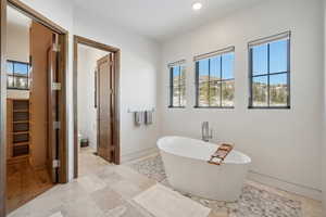Bathroom featuring a soaking tub, toilet, recessed lighting, and baseboards