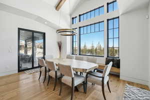 Dining space featuring high vaulted ceiling, light hardwood / wood-style flooring, beam ceiling, and a notable chandelier