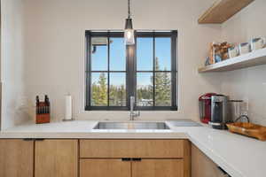 Kitchen with a sink, light countertops, decorative light fixtures, and open shelves