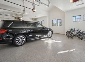 Garage with a garage door opener, recessed lighting, and baseboards