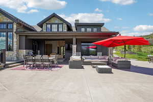 Back of property featuring stone siding, an outdoor living space, a patio area, and outdoor dining space
