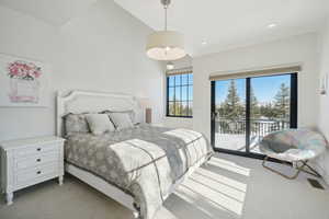 Carpeted bedroom with lofted ceiling and access to outside