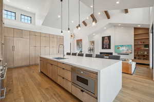 Kitchen with stainless steel microwave, a spacious island, a towering ceiling, beam ceiling, and sink