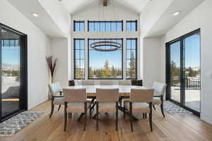 Dining area featuring high vaulted ceiling, light wood-type flooring, beamed ceiling, and an inviting chandelier