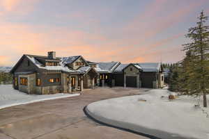 View of front of house with stone siding, a chimney, an attached garage, and a porch