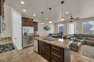 Kitchen featuring ceiling fan, backsplash, a center island with sink, sink, and appliances with stainless steel finishes