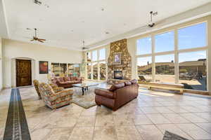 Living room with light tile patterned flooring, a fireplace, and a towering ceiling