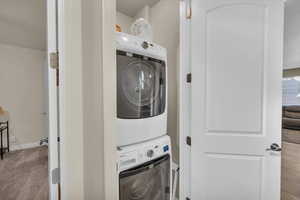 Washroom featuring light carpet and stacked washer and dryer