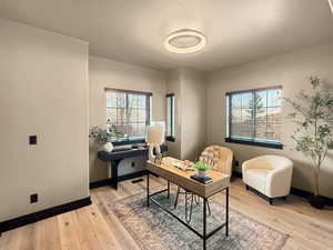 Home office featuring light wood-type flooring and a textured ceiling