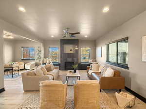 Living room with ceiling fan, a tile fireplace, and light hardwood / wood-style flooring