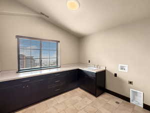 Clothes washing area featuring sink, hookup for a washing machine, electric dryer hookup, and cabinets