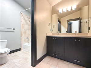 Full bathroom with lofted ceiling, tiled shower / bath, tile patterned flooring, vanity, and toilet