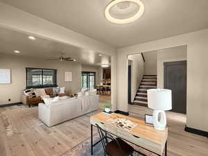 Living room with ceiling fan and light hardwood / wood-style flooring