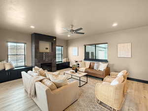 Living room with ceiling fan, light hardwood / wood-style floors, plenty of natural light, and a tile fireplace