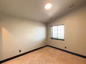 Carpeted spare room featuring lofted ceiling