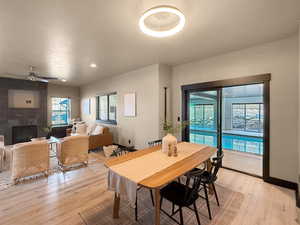 Dining room with ceiling fan, a fireplace, and light hardwood / wood-style flooring