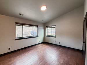 Unfurnished room featuring dark wood-type flooring and lofted ceiling