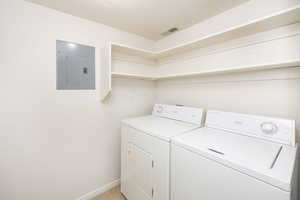 Clothes washing area featuring washer and clothes dryer and electric panel