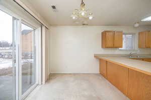 Kitchen with sink, pendant lighting, a notable chandelier, and a healthy amount of sunlight