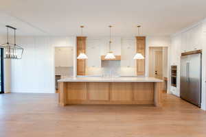 Kitchen with white cabinets, pendant lighting, a large island with sink, and stainless steel built in fridge