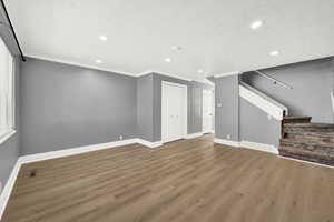 Unfurnished living room with wood-type flooring, crown molding, and a textured ceiling